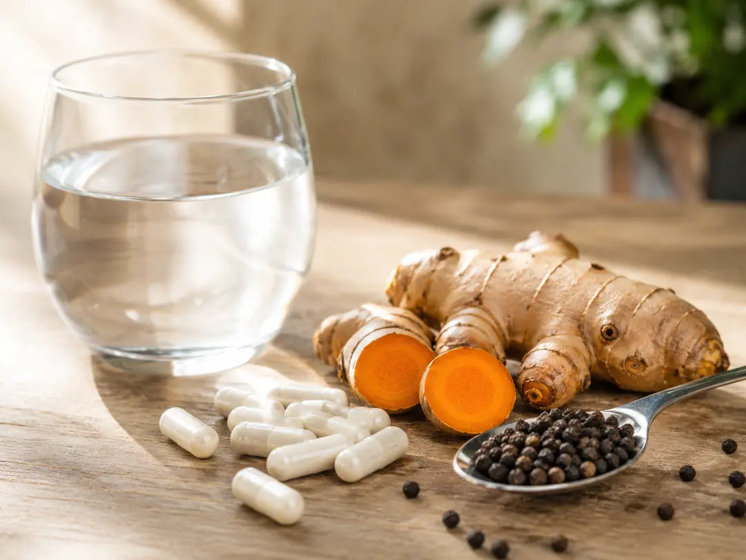 Capsule ArtiZynt accanto agli ingredienti naturali: radice di curcuma, pepe nero in grani
