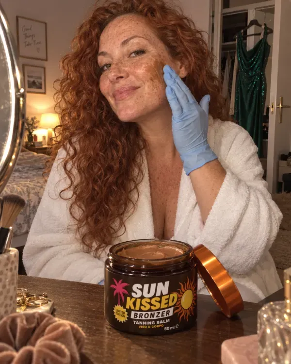 Roberta, capelli rossi ricci, stende Sun Kissed con il guanto la sera, con l'abito da cerimonia appeso all'armadio