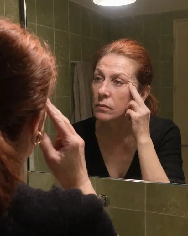 Donna allo specchio del bagno che tocca le zampe di gallina