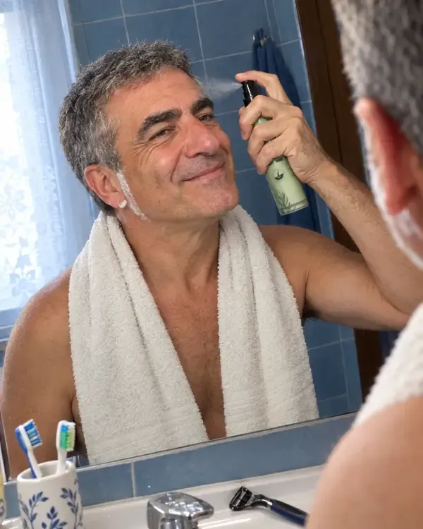 Giorgio allo specchio dopo la barba che si spruzza il rosmarino sulle tempie
